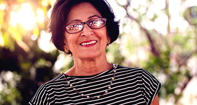 Mulher de óculos sorrindo com as vantagens do seguro prestamista